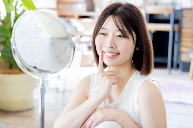 鏡で歯の色味を確認する女性（イメージ）
